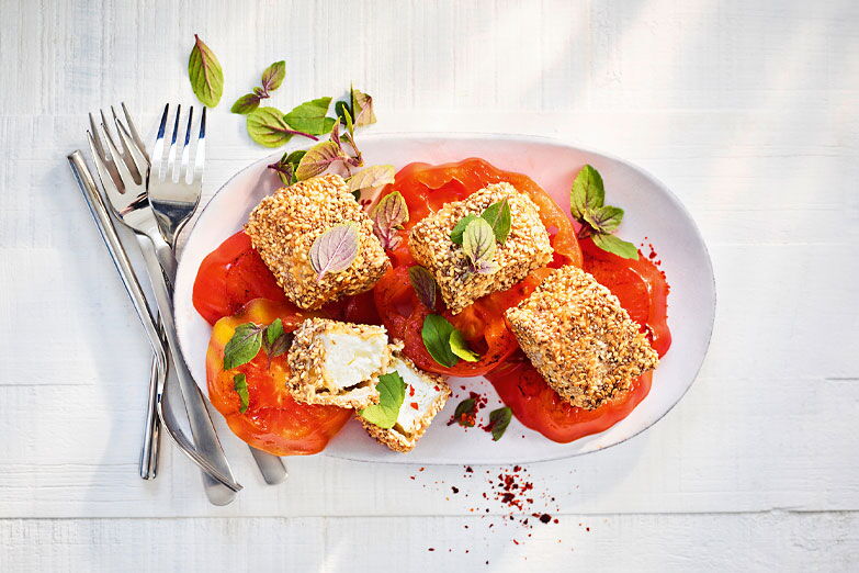 Foto von Feta in Chia-Sesam-Knusperhülle auf Tomaten